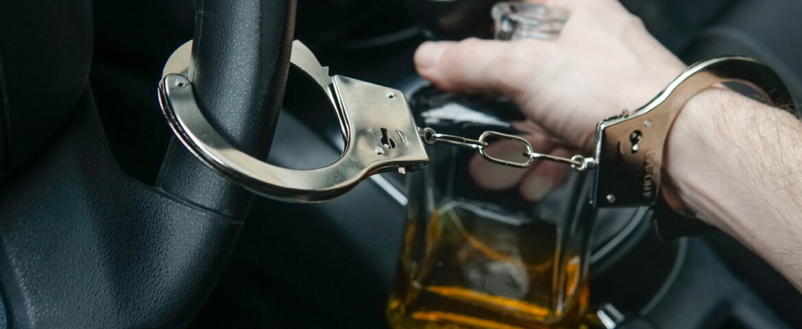 Man in handcuffs holding an alcohol bottle inside a car representing DUI arrest and DUI bail bonds San Diego process