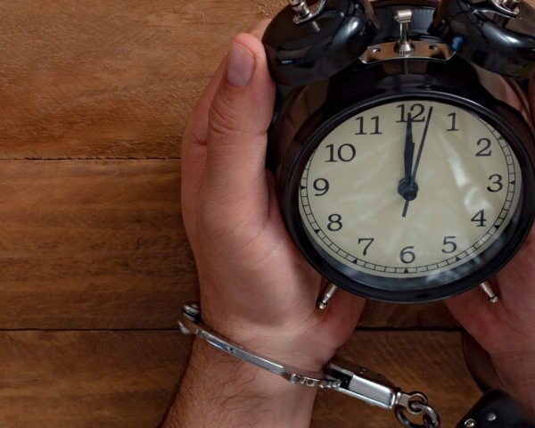 Handcuffed individual sitting under a clock symbolizing urgency after arrest and the importance of National City bail bonds in early legal action