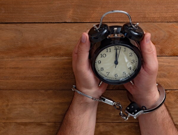 Handcuffed individual sitting under a clock symbolizing urgency after arrest and the importance of National City bail bonds in early legal action