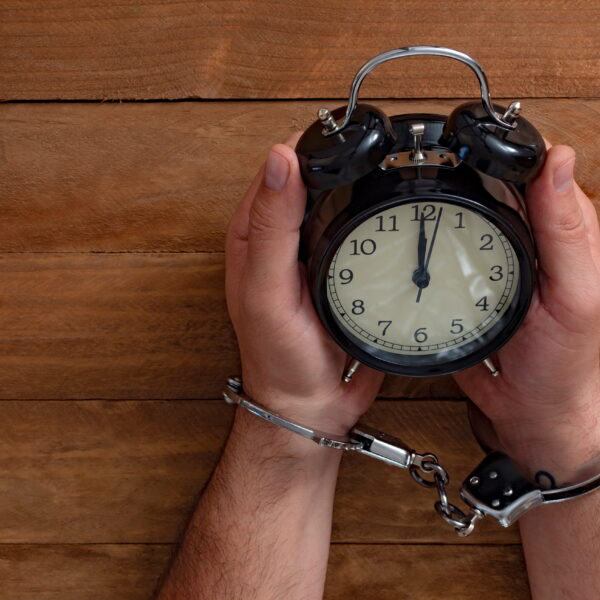 Handcuffed individual sitting under a clock symbolizing urgency after arrest and the importance of National City bail bonds in early legal action