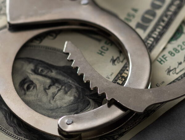 Handcuffs placed over hundred-dollars representing bail and financial considerations in Downtown San Diego bail bonds situations