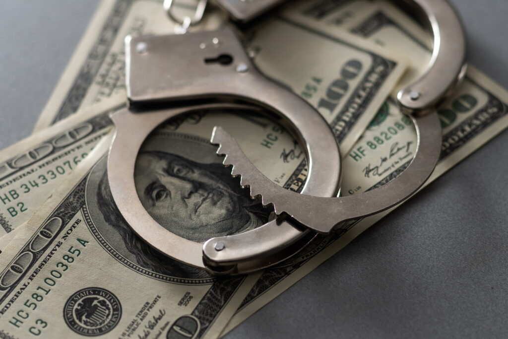 Handcuffs placed over hundred-dollars representing bail and financial considerations in Downtown San Diego bail bonds situations