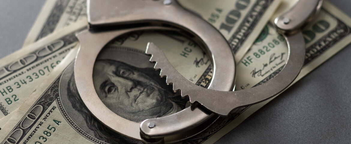 Handcuffs placed over hundred-dollars representing bail and financial considerations in Downtown San Diego bail bonds situations
